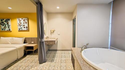 a hotel room with a bed and a bath tub at Recenta Suite Phuket Suanluang in Phuket Town
