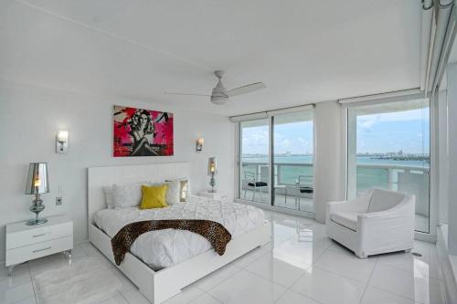 a white bedroom with a bed and a chair at Seas The Day! Complete Panoramic Water Views in Miami