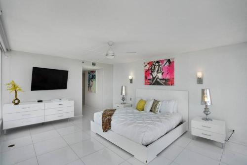 a white bedroom with a bed and a flat screen tv at Seas The Day! Complete Panoramic Water Views in Miami