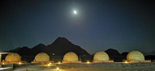 Eine Gruppe von Kuppeln in der Nacht mit dem Mond in der Unterkunft Bubbles Oasis Camp Wadi Rum in Wadi Rum