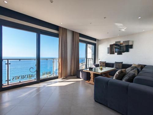 a living room with a blue couch and large windows at RS Apartments - AL HOCEIMA in Al Hoceïma