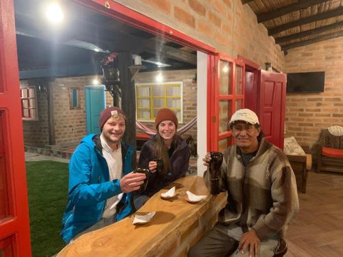 un grupo de tres personas sentadas en una mesa de madera en Casa Victoria, habitaciones y zona de camping en Otavalo