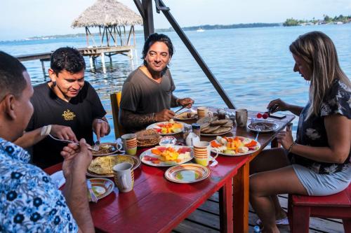 Eine Gruppe von Menschen, die an einem Tisch sitzen und Essen essen. in der Unterkunft Carmen's place in Bastimentos