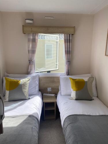 two beds in a small room with a window at Cookies Den in Weymouth