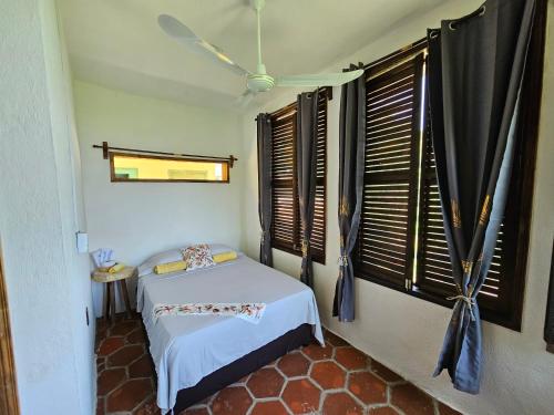 a bedroom with a bed in a room with windows at Hotel Quinto Sol in Mazunte