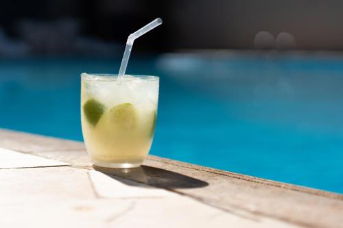 a drink sitting on a table next to a pool at San Rafael Comfort Class Hotel in Foz do Iguaçu