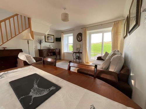 un salon avec un canapé et une table dans l'établissement Buttercup Cottage, à Killean
