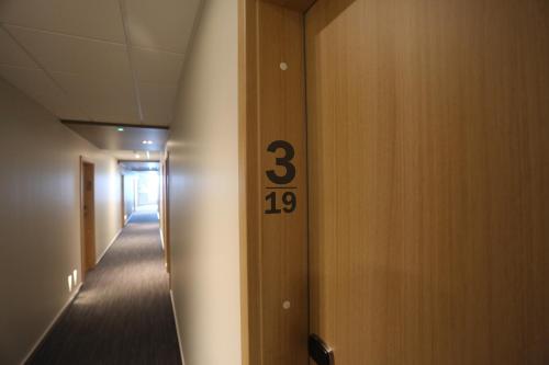 a hallway with a door with the number three on it at Hotel Vellir in Hafnarfjördur