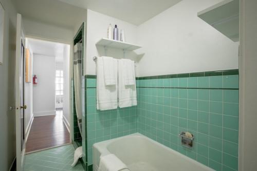 ein Badezimmer mit einer Badewanne und einer grün gefliesten Wand in der Unterkunft Seaside Serenity 1 BR Apt with balcony near Alki in Seattle