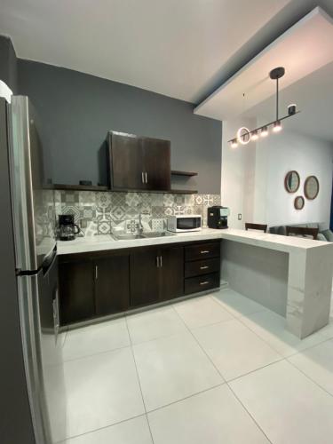 a kitchen with brown cabinets and a white tile floor at Depas Mololoa in Tepic
