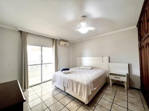 Un dormitorio con una cama blanca y una ventana. en Jurere, en Meia Praia