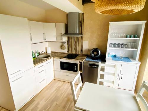a small kitchen with white cabinets and a sink at Nida Loft with SPA and Tennis court in Nida