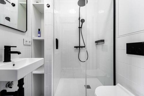 a white bathroom with a shower and a sink at Mokotów Premium Studio in Warsaw