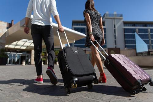 a man and a woman walking with their luggage at Esplendor by Wyndham Mendoza in Mendoza