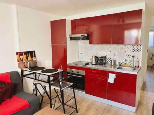 a kitchen with red cabinets and a table in a room at Appartement Ensoleillé à 15 minutes de Paris in Vitry-sur-Seine