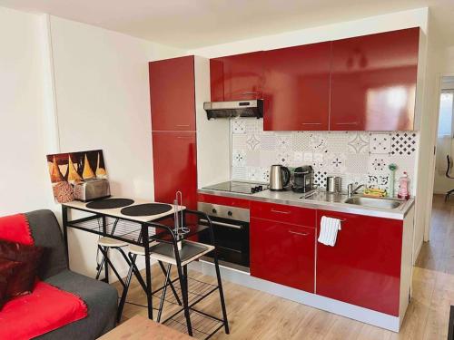 Una cocina con gabinetes rojos y una mesa en una habitación. en Appartement Ensoleillé à 15 minutes de Paris, en Vitry-sur-Seine