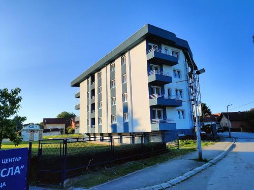 Apartman Centar Kozarska Dubica في Bosanska Dubica: مبنى ابيض كبير بسقف اسود