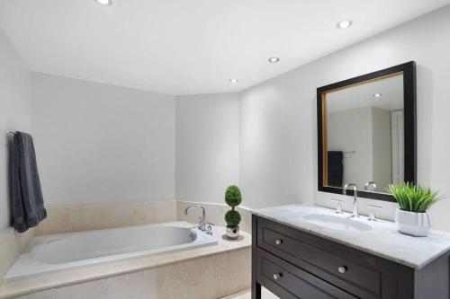 een badkamer met een bad, een wastafel en een spiegel bij Good Morning Beautiful! Direct Water Views in Miami