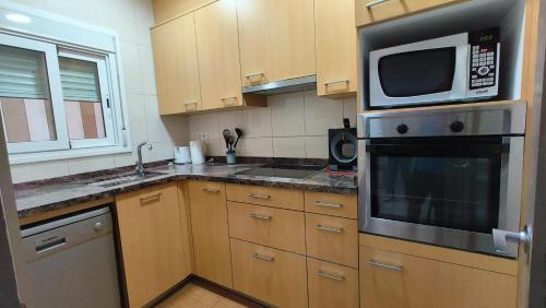 cocina con armarios de madera y microondas en Apartments Cal Benet, en Camarasa