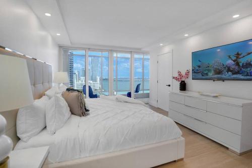 a white bedroom with a large bed and a large aquarium at Make It Happen! Brand New with Amazing Water Views in Miami