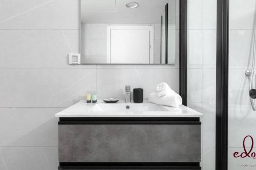 een witte badkamer met een wastafel en een spiegel bij דירה למשפחה 50 מטר מהים - By Edom in Eilat