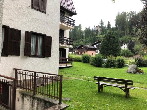 a park bench sitting in the grass next to a building at Monolocale Bixio a Ponte di Legno in Ponte di Legno