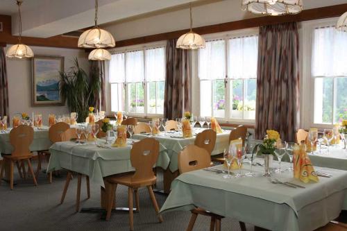 ein Esszimmer mit Tischen, Stühlen und Fenstern in der Unterkunft Gasthaus Waldhaus in Melchtal