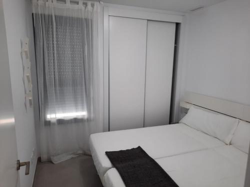 a white bedroom with a bed and a window at Almar Relax in Daimuz