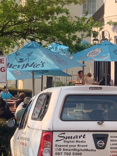 a white car parked in front of blue umbrellas at Kaneel Suiker in Paarl