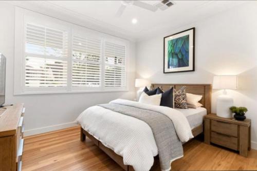 a bedroom with a bed and a desk and a window at Charming Bayside Home in Burraneer