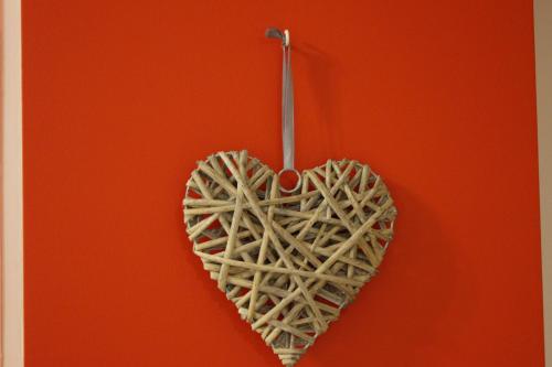 a heart shaped object hanging on a red wall at Ferme Sainte Marie in Rémilly