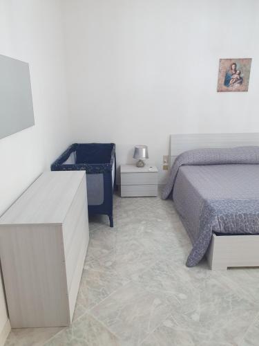ein Schlafzimmer mit einem Bett und einer weißen Wand in der Unterkunft Appartamento Rosa dei Venti in Marsala