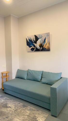 a blue couch in a room with a painting on the wall at DendroBak GuestHouse in Stepʼanavan