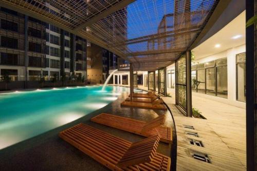 a swimming pool with chaise lounges in a building at Selayang 18 Residences (with Wifi 300Mbps) in Batu Caves