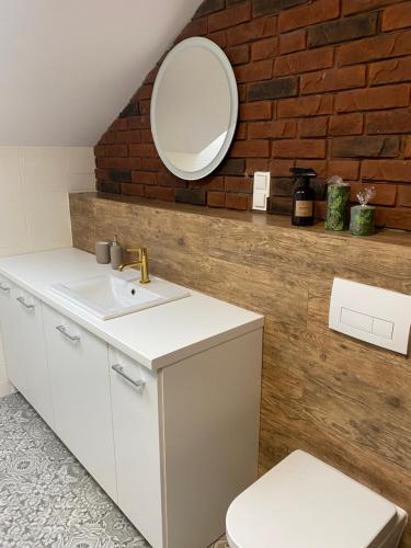 baño con lavabo y espejo en una pared de ladrillo en Apartamenty na Wzgórzu Boho 2, en Zagnańsk