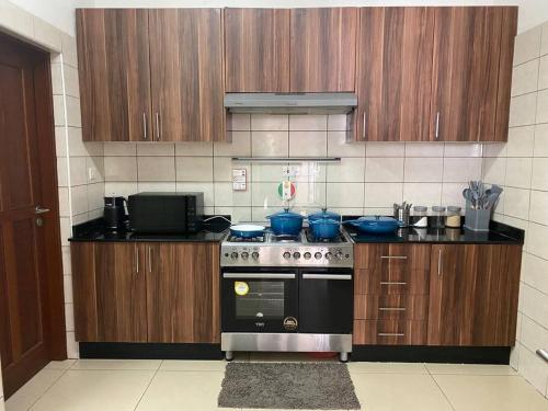a kitchen with a stove and some wooden cabinets at Homely 2-Bedroom at Victoria Place in Dar es Salaam