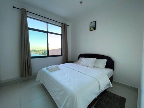 a bedroom with a large bed with a large window at Homely 2-Bedroom at Victoria Place in Dar es Salaam