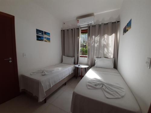 1 dormitorio con 2 camas y ventana en Pousada Maré en Cumuruxatiba