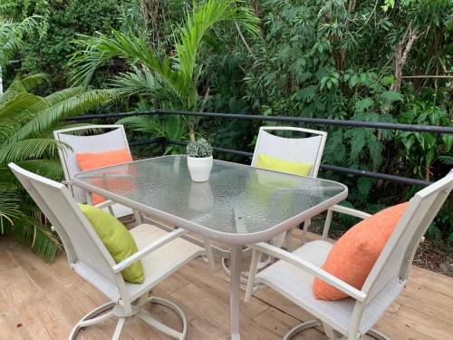 un patio con mesa de cristal y 4 sillas en Sugarfields Villa en Jolly Harbour