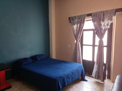a bedroom with a blue bed and a window at Casa Flores in Zacatecas