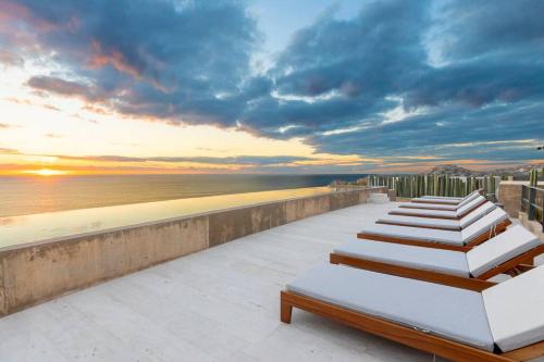 a row of chaise lounges on a balcony overlooking the ocean at Stunning Oceanview Condo in San José del Cabo