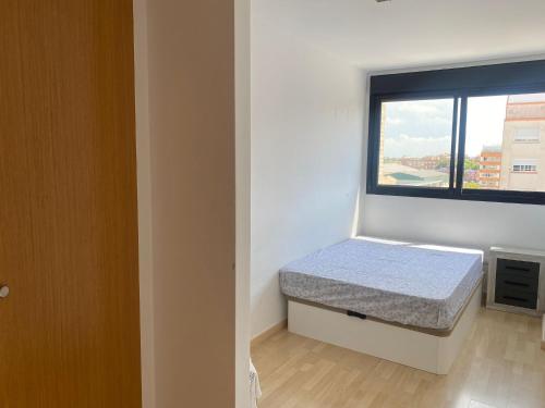 um pequeno quarto com uma cama e uma janela em Habitaciones confort em Benetúser