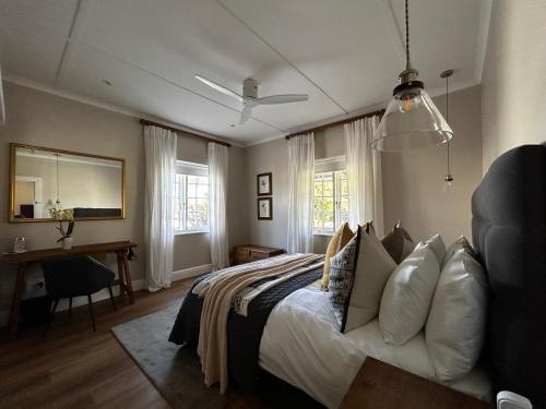 a bedroom with a bed and a desk and windows at Blu Belle Lagoon Cottage in Knysna