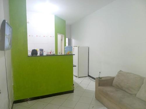a living room with a couch and a green wall at Kitnet praia de Atalaia, Aracaju - Sergipe in Aracaju