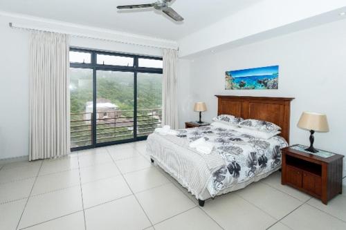 a bedroom with a bed and a large window at The Herolds Bay in Herolds Bay