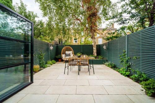 a patio with a table and chairs in a garden at Cozy 2 Bedroom garden flat in London
