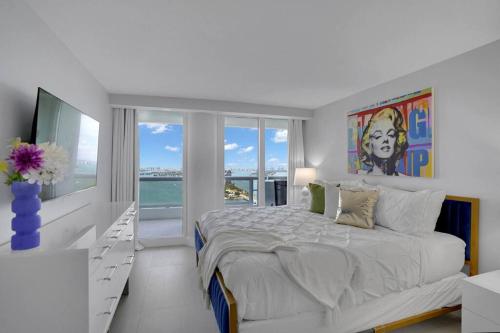 a white bedroom with a large bed and a window at Cloud Nine! Direct Water Views of Bay & Ocean! in Miami
