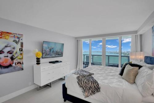 a white bedroom with a bed and a large window at Cloud Nine! Direct Water Views of Bay & Ocean! in Miami