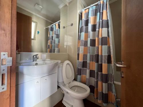 uma casa de banho com um lavatório, um WC e uma cortina de chuveiro. em Departamento Holiday Park Reñaca 306 Familiar em Viña del Mar