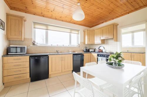 a kitchen with wooden cabinets and a white table with chairs at Farnetra Lodge in Clogher